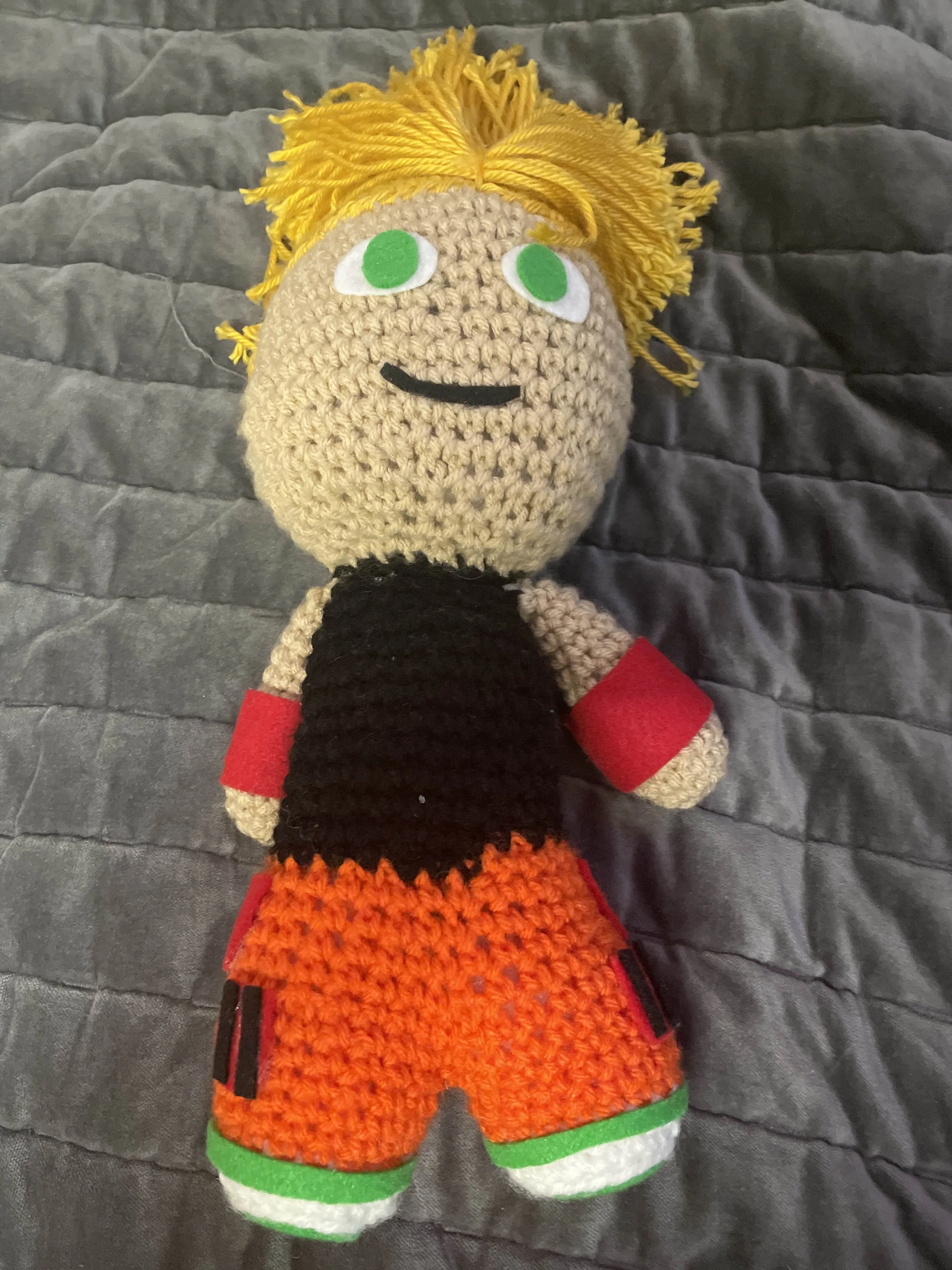Pale skinned crochet doll with blonde hair and green eyes